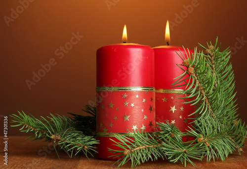 Photo: Two candles and christmas tree, on brown background Two candles and christmas tree, on brown background