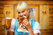 Junge Frau im Dirndl vor einer Almhütte