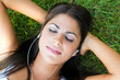 Woman lying on grass listening to music outdoors