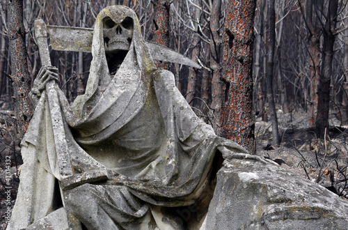 Photo: statue représentant la mort devant une forêt incendiée statue représentant la mort devant une forêt incendiée