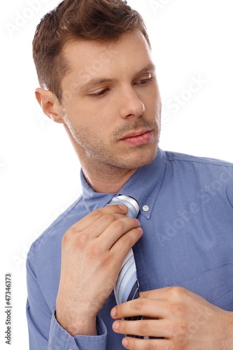 Photo: Serious man adjusting tie Serious man adjusting tie