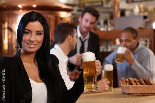 Photo: Young woman in pub with mug of beer Young woman in pub with mug of beer