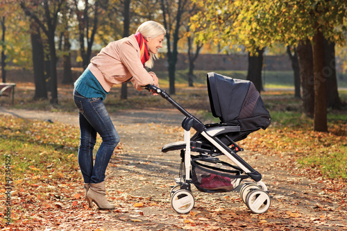 Photo: Smiling mother looking at her child in a baby stroller Smiling mother looking at her child in a baby stroller
