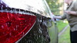 Unrecognizable female person washing car by sponge