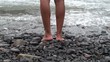 A guy standing on a volcanic stone beach, en relaxation