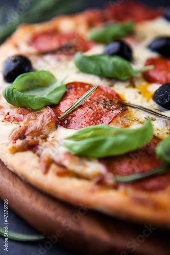 Photo: Close up of pizza with salami and herbs Close up of pizza with salami and herbs
