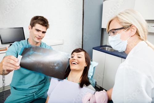Photo: Dentist With Female Assistant Showing X-Ray Image To Patient Dentist With Female Assistant Showing X-Ray Image To Patient