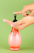 woman squeezing lotion on her hand, on green background
