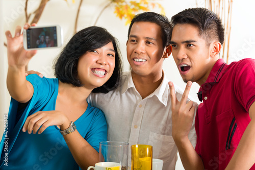 Photo: Asian friends taking pictures with mobile phone Asian friends taking pictures with mobile phone
