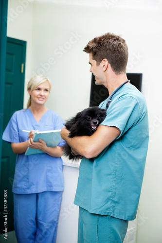 Photo: Veterinarian Doctor With A Dog Looking At Female Nurse Holding C Veterinarian Doctor With A Dog Looking At Female Nurse Holding C