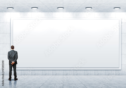 Photo: Business person standing near a blank billboard Business person standing near a blank billboard