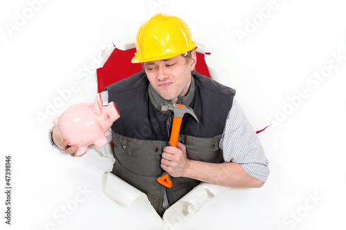 Photo: Laborer holding hammer and piggy bank Laborer holding hammer and piggy bank