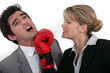 businesswoman hitting a man with a boxing glove