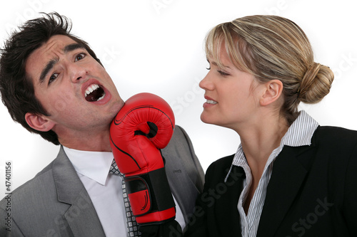 Photo: businesswoman hitting a man with a boxing glove businesswoman hitting a man with a boxing glove