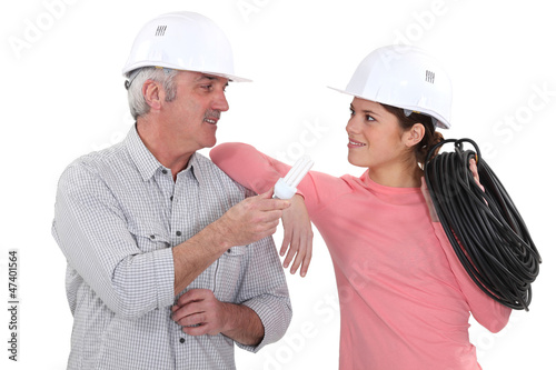 Photo: electricians talking and holding a bulb and a wire electricians talking and holding a bulb and a wire