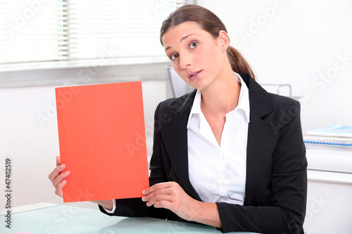 Photo: Young woman holding up a red file Young woman holding up a red file