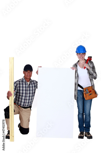 Photo: Carpenter and plumber stood with marketing board Carpenter and plumber stood with marketing board