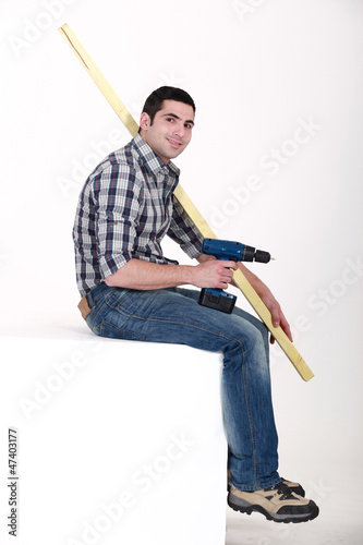 Photo: Man sat with power drill and length of wood Man sat with power drill and length of wood