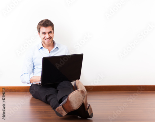 Photo: Young man using a laptop on the floor Young man using a laptop on the floor