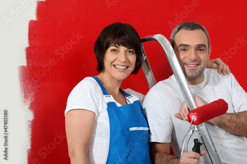 Photo: Couple painting wall red Couple painting wall red