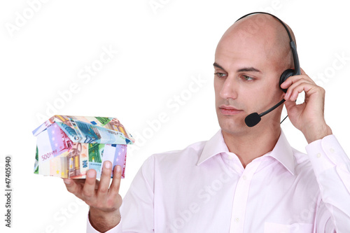 Photo: Call center agent holding a house made out of money Call center agent holding a house made out of money