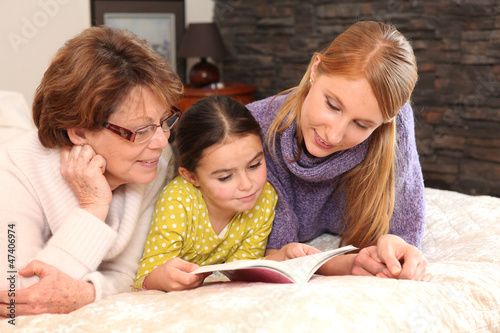 Photo: Three generations reading a book together Three generations reading a book together