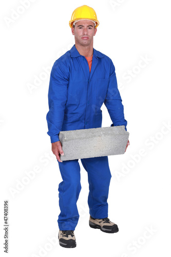 Photo: Labourer lifting a heavy block Labourer lifting a heavy block