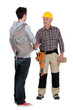 senior craftsman and young apprentice shaking hands
