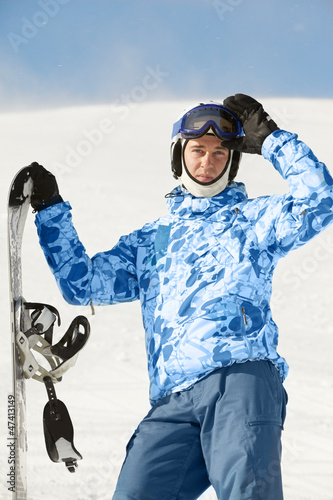 Photo: Snowboarder in ski suit and helmet stands with snowboard Snowboarder in ski suit and helmet stands with snowboard