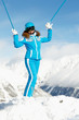 Young woman in blue ski suit stands  on top of hill