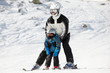 Father supports his child when they slide on alpine skis