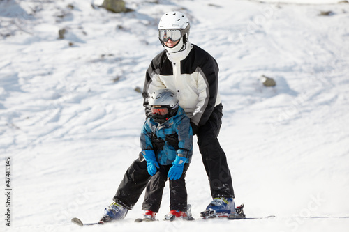 Photo: Father supports his child when they slide on alpine skis Father supports his child when they slide on alpine skis