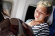 Young beautiful woman reads magazine in airplanee