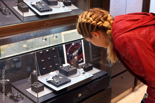 Photo: woman with braid considers jewelry in a jewelry store. woman with braid considers jewelry in a jewelry store.