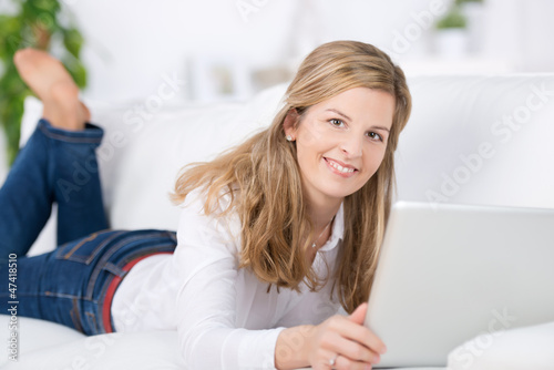 Photo: lächelnde frau mit laptop auf dem sofa lächelnde frau mit laptop auf dem sofa