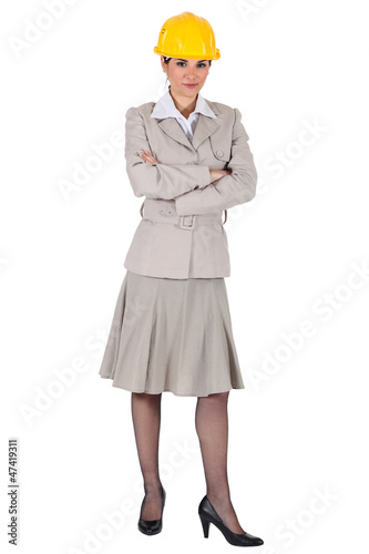 Photo: Female wearing a trench coat and a hardhat. Female wearing a trench coat and a hardhat.