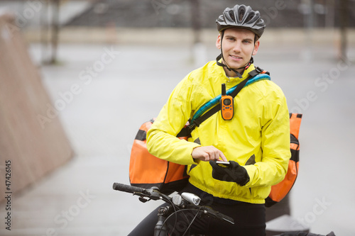 Photo: Male Cyclist With Courier Bag Using Mobile Phone On Street Male Cyclist With Courier Bag Using Mobile Phone On Street