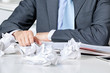 Businessman Sitting At Desk With Crumpled Papers