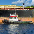 Tugboat guiding a huge oil tanker