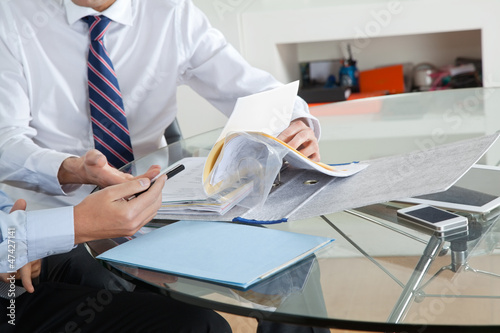 Photo: Businessman With Colleague Discussing Paperwork Businessman With Colleague Discussing Paperwork