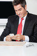 Businessman Using Cell Phone At Desk