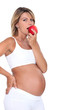 Pregnant woman biting into red apple