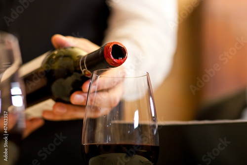 Photo: Waiter serving red wine with bottle at the restaurant Waiter serving red wine with bottle at the restaurant