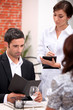 a couple ordering at the restaurant, a waitress is writing