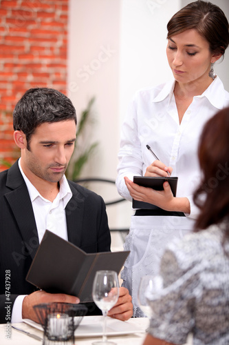 Photo: a couple ordering at the restaurant, a waitress is writing a couple ordering at the restaurant, a waitress is writing