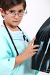 little boy dressed as a doctor looking at a x-ray image