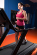 Beautiful smiling girl running on treadmill