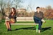 Angry young couple sitting away outdoors on a bench.
