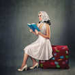 Photo: Retro woman with sunglasses and suitcase reading book Retro woman with sunglasses and suitcase reading book