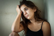 Sad hispanic girl sitting in a dark corner